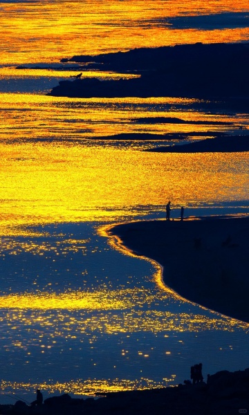 金滩衔暮色，人影浸流光